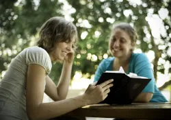 two women reading a book and smiling