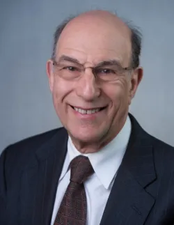 Headshot of smiling man in glasses, suit and tie