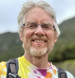 Andrew Kang Bartlett smiling and wearing a tie-dye tshirt