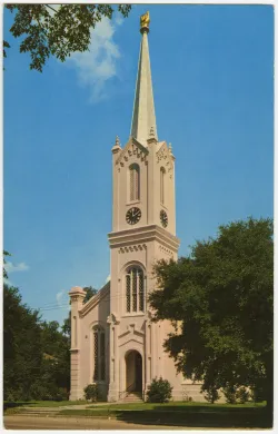 A church building with a 10-foot-tall gold-leaf-covered sculpture of a human hand at the top of its steeple. 