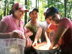 A small group of women make masa in a large bowl
